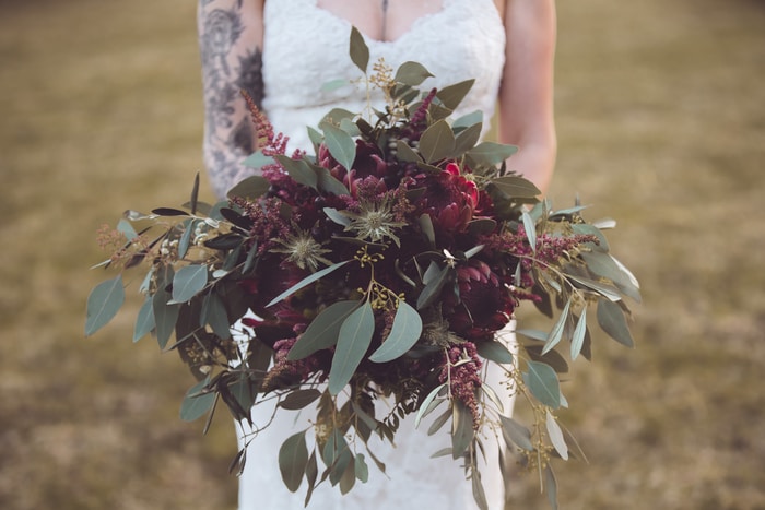 woman in white floral lace wedding dress holding red and green plant