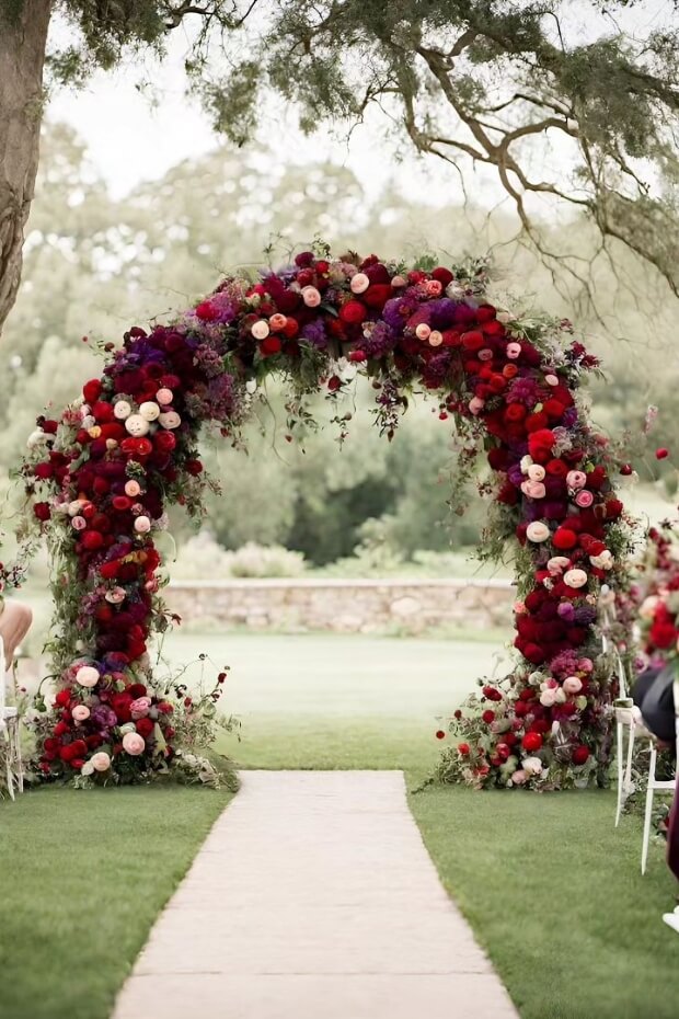 Archway-style wedding arch with red and purple flowers