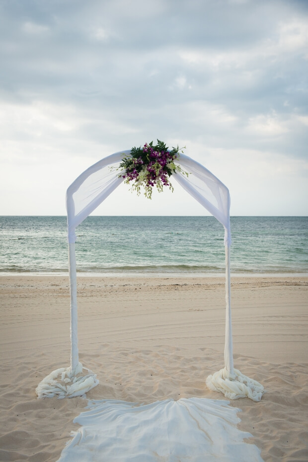 Beach wedding arch with white canopy and flowers