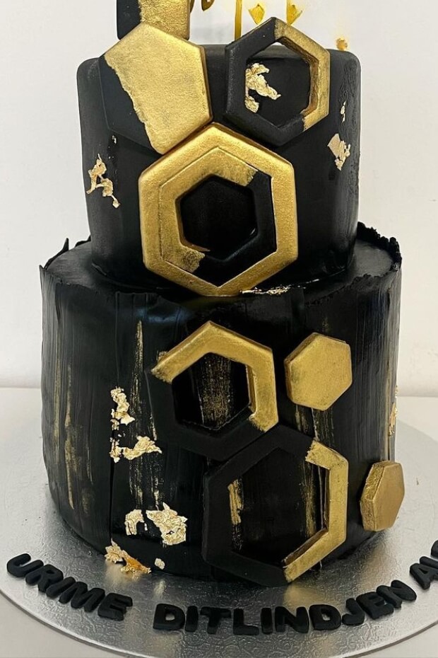 Hexagonal black and gold wedding cake with gold foil accents and gold border