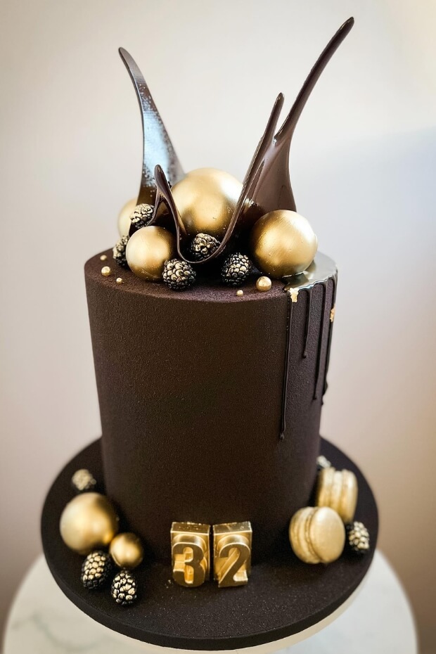 Glamorous black and gold wedding cake with gold balls and chocolate drops
