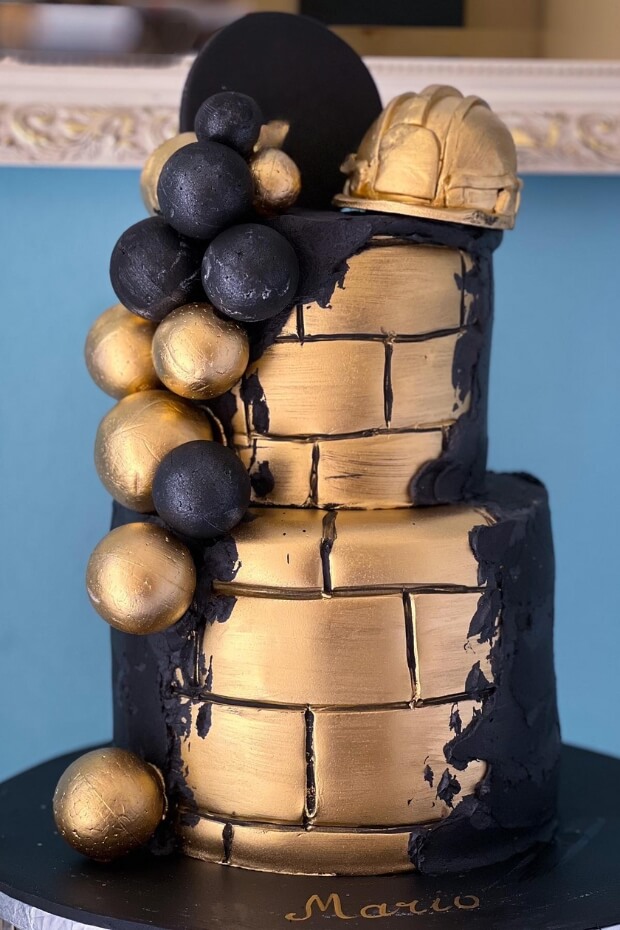 Unique black and gold wedding cake with gold brick wall and black stones base