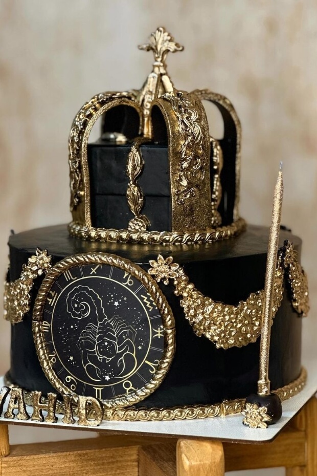 Regal black and gold wedding cake adorned with crown, clock, and golden border