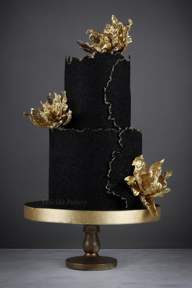 Magnificent black and gold wedding cake with gold flowers on gold metal stand