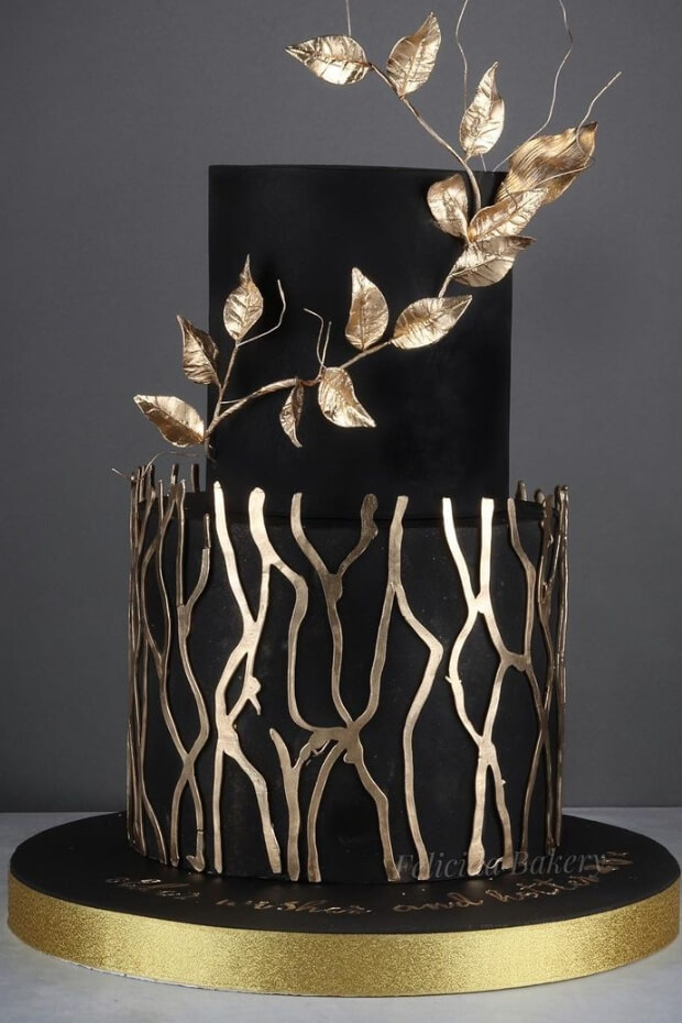 Exquisite black and gold wedding cake with intricate gold leaf details and golden branch
