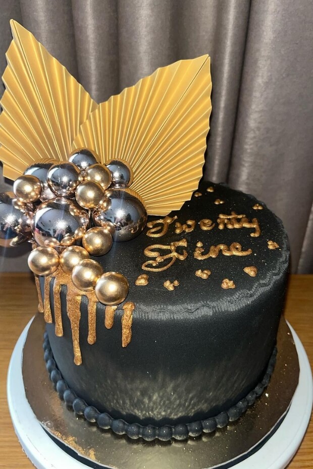 Stunning black and gold wedding cake with golden butterfly and bubbles