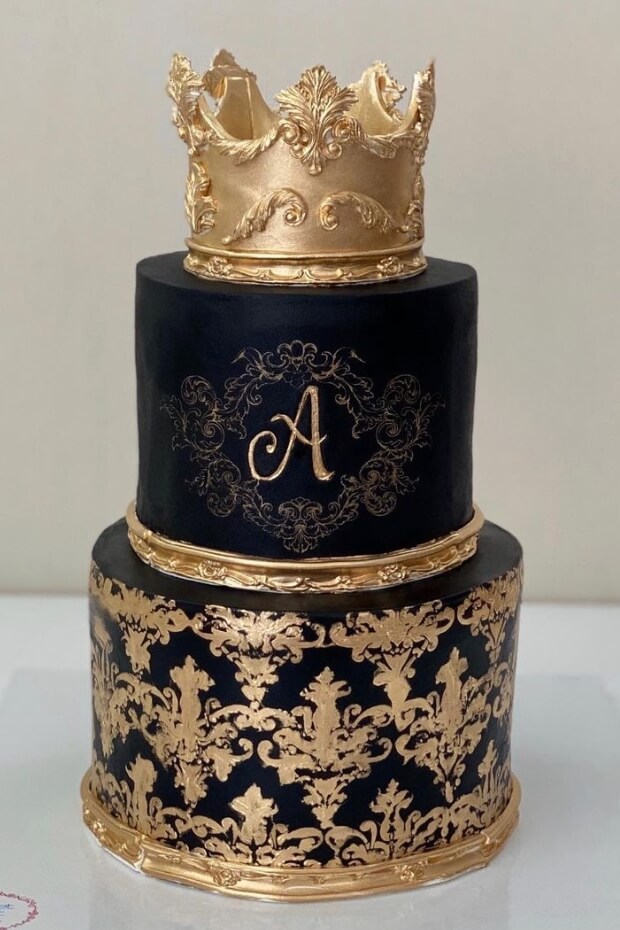 Opulent black and gold wedding cake with grand golden crown and intricate gold designs