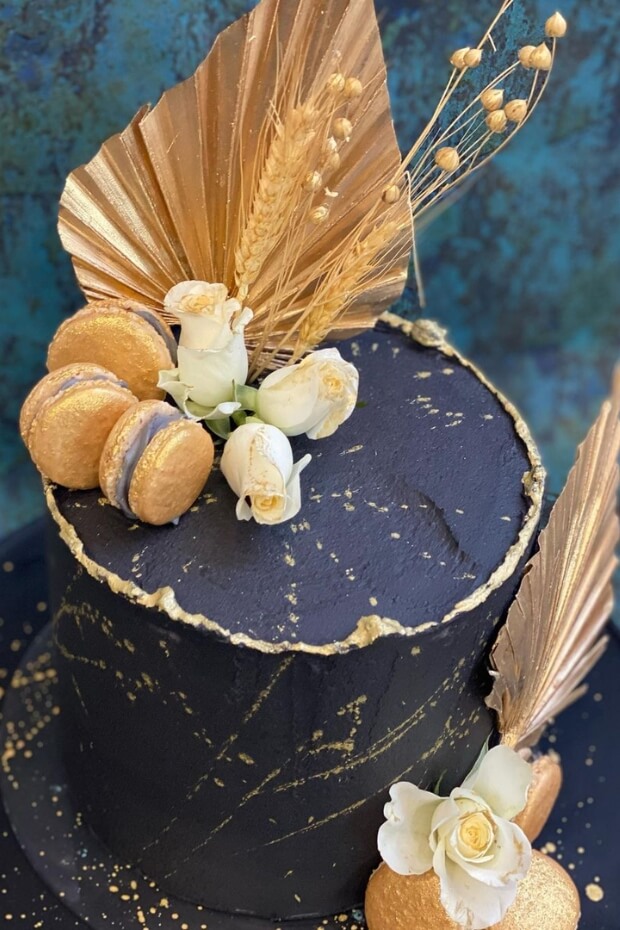 Beautiful black and gold wedding cake with gold leaf and edible flowers