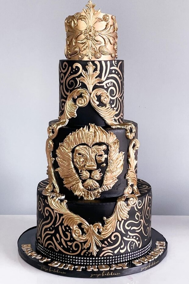 Grand black and gold wedding cake with intricate gold leaf details and lion's head