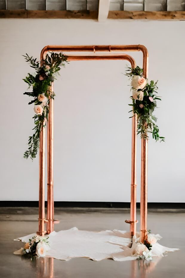 Copper pipe wedding arch with lush greenery and flowers