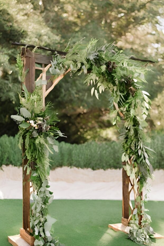 Natural rustic wooden wedding arch with greenery and flowers