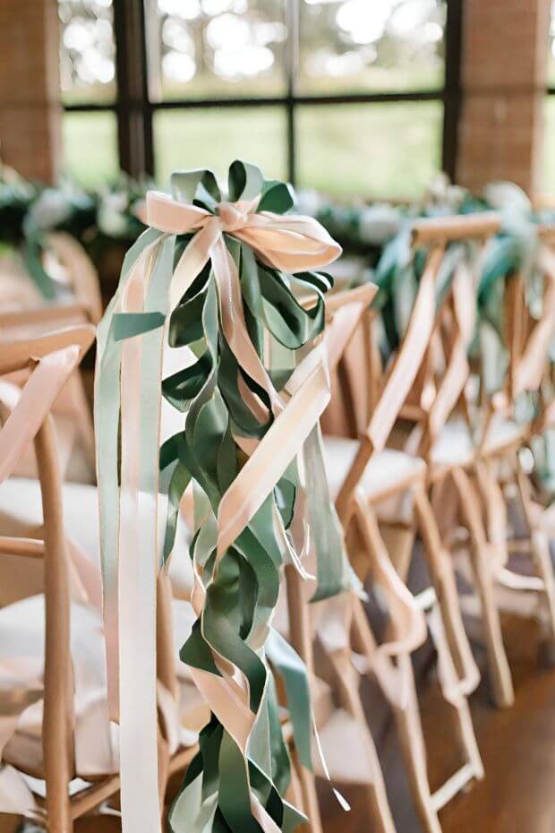 Green and white ribbon adorned chairs at wedding venue
