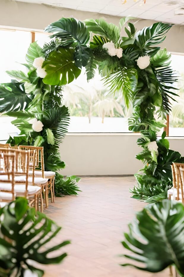 Tropical foliage wedding arch with lush green and white decoration