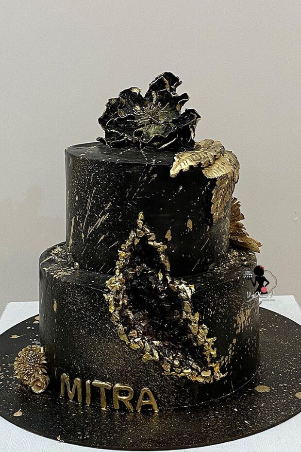 Elegant two-tiered black and gold wedding cake with intricate gold details