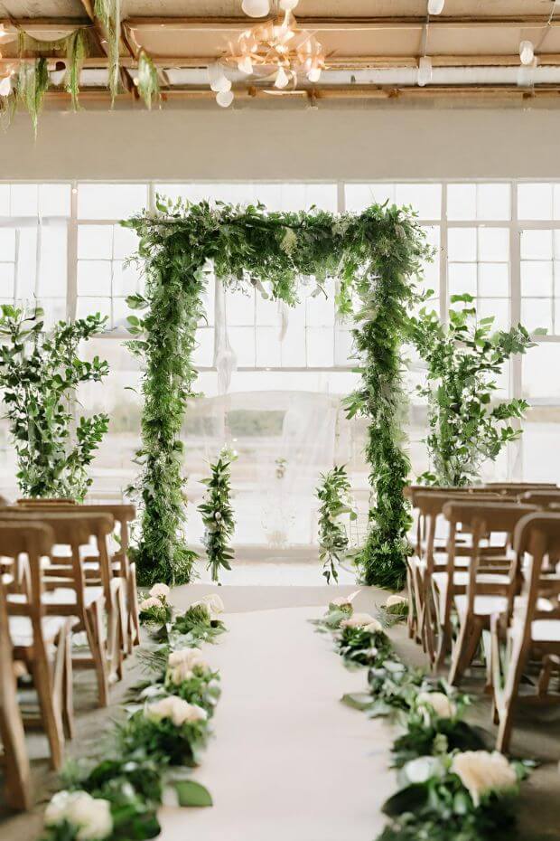 Wedding aisle with green foliage and white chairs