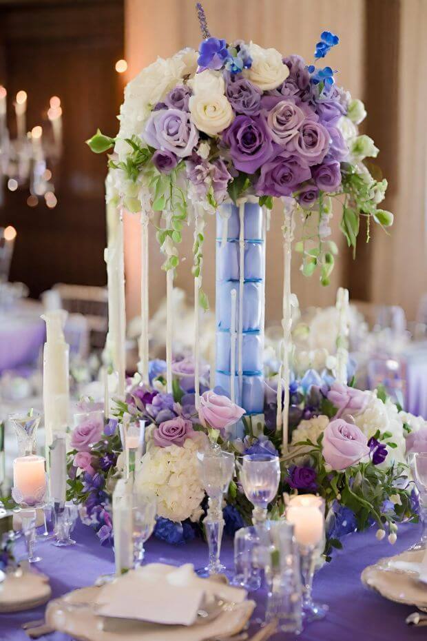 Tall vase centerpiece with purple and white flowers and greenery