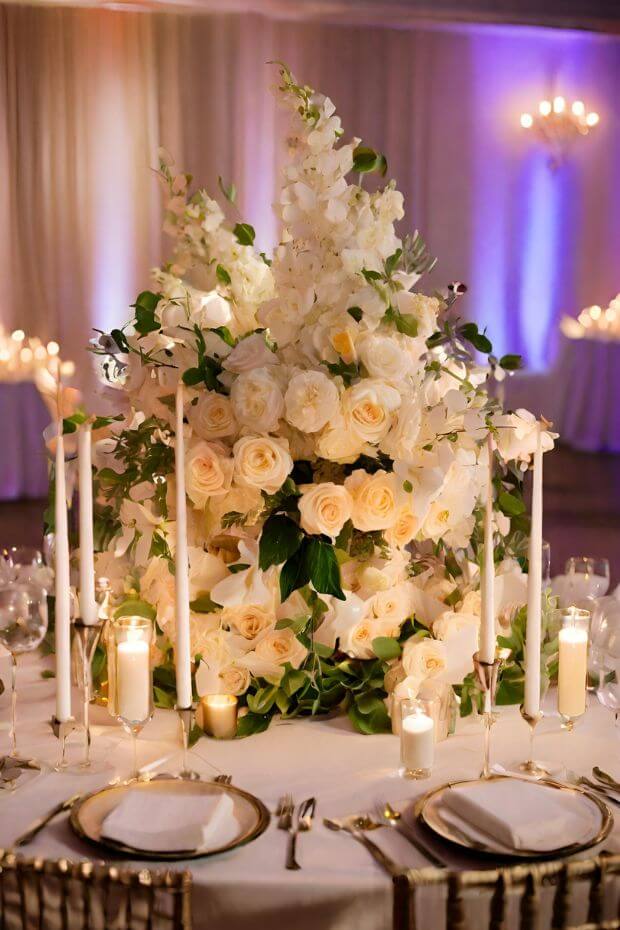White roses and greenery centerpiece with candles on silver platter