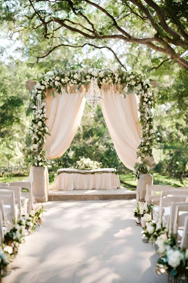 Wooden platform wedding arch with greenery and white flowers
