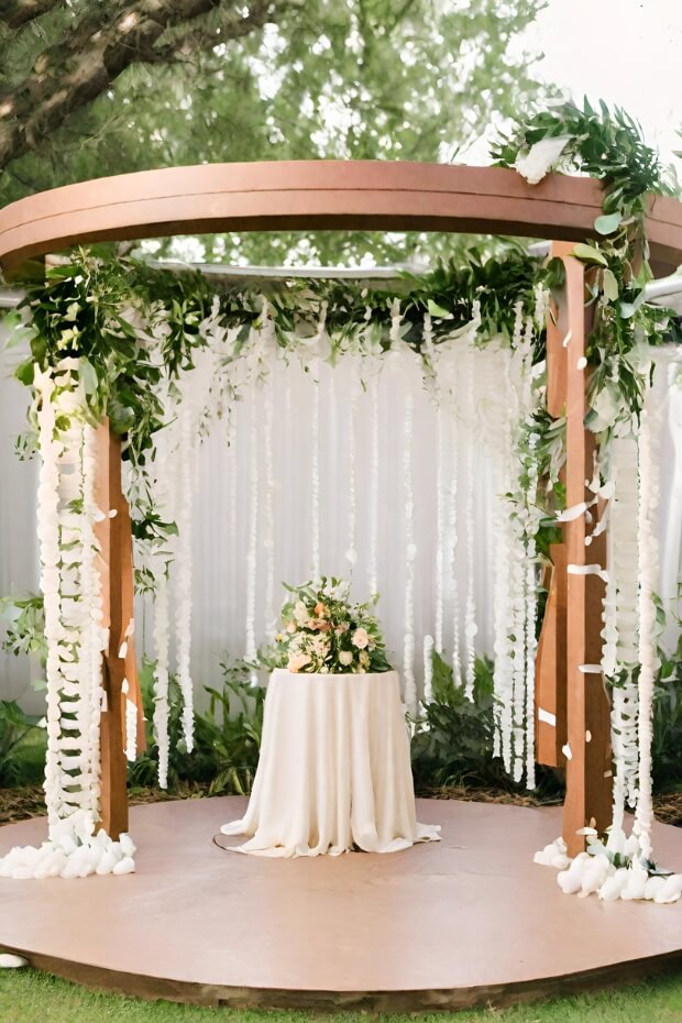 Wooden wedding arch with lush greenery and white flowers