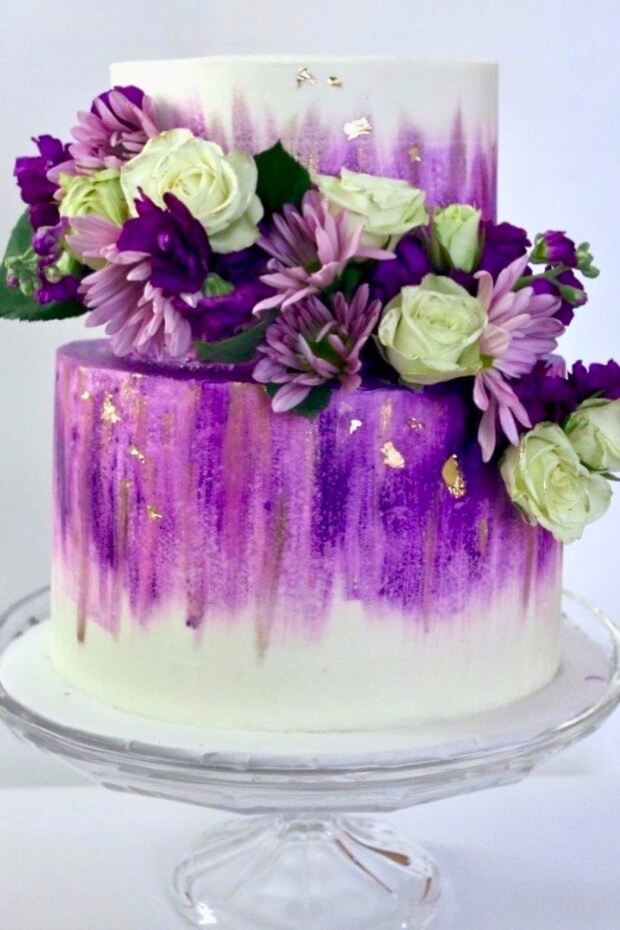 Beautiful wedding cake with purple and gold accents and floral decorations