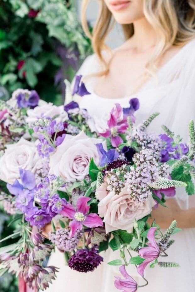 Bride holding purple bouquet of flowers