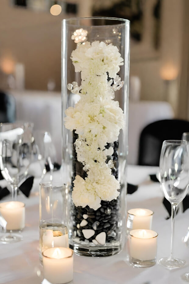 Clear vase with white flowers surrounded by candles