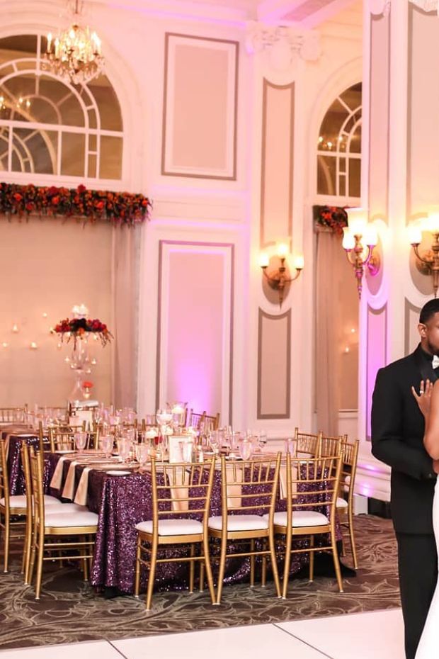Elegant couple standing amidst grand purple and gold wedding decorations