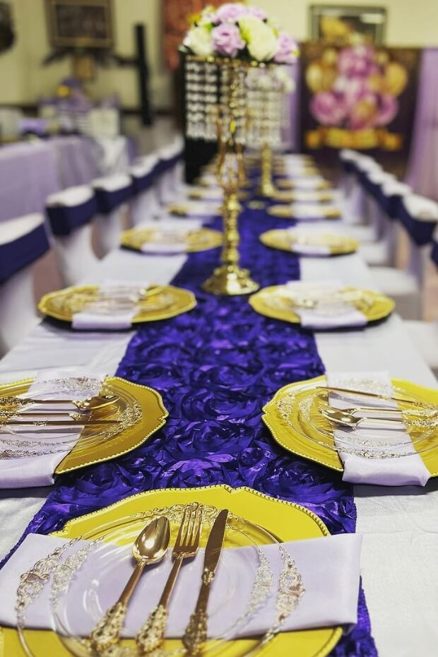 Formal dinner party table set with purple and gold linens and place settings