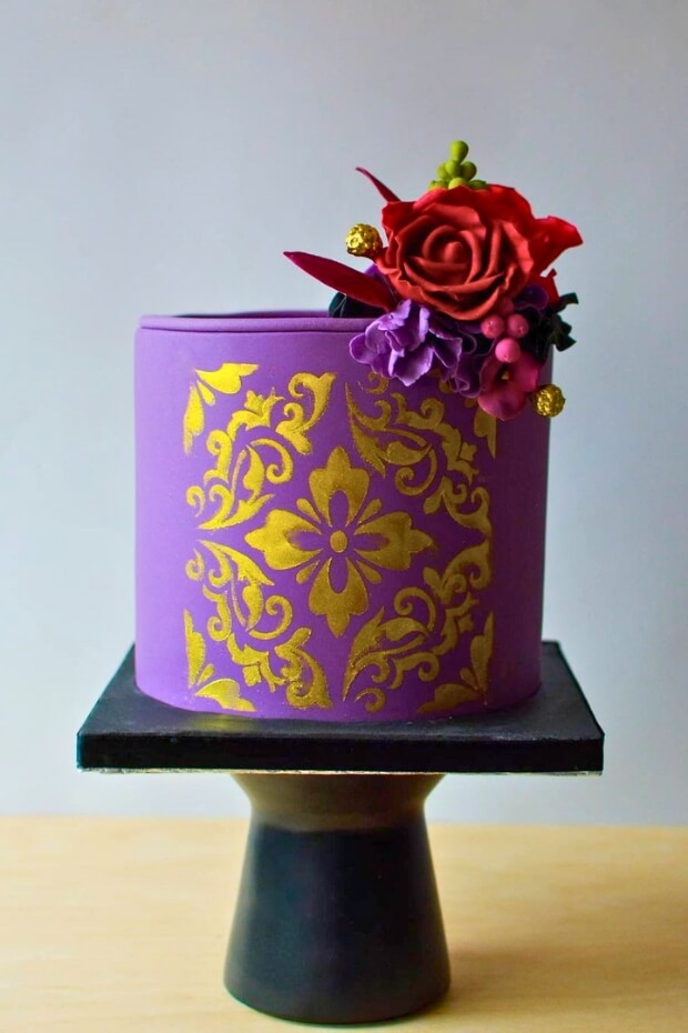 Luxurious purple and gold wedding cake centerpiece with decorative elements