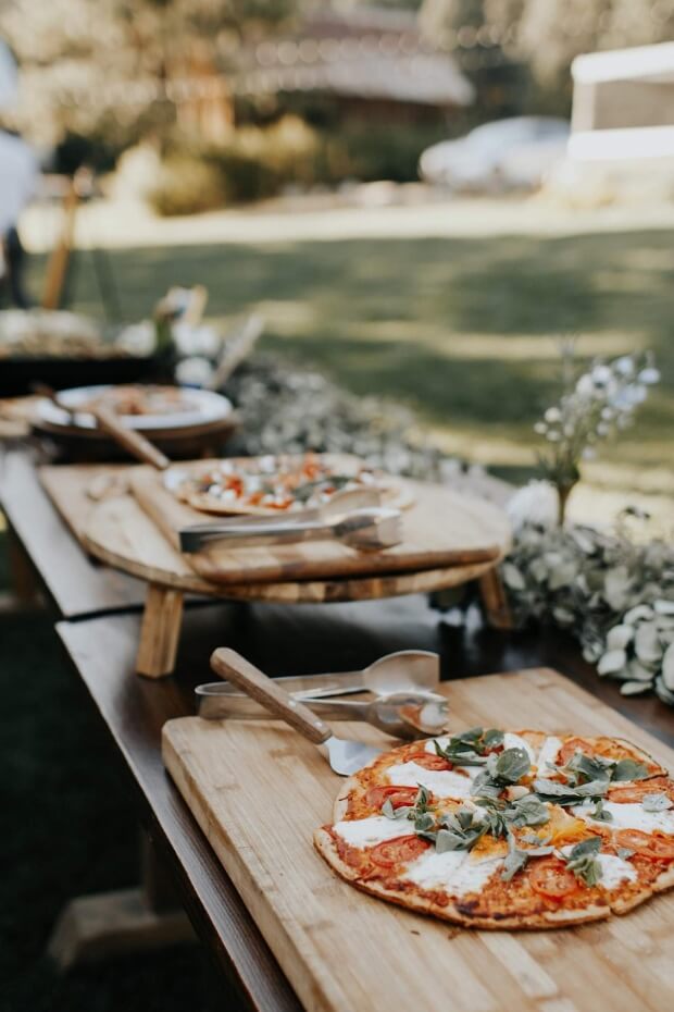 Outdoor wooden table with assorted pizzas
