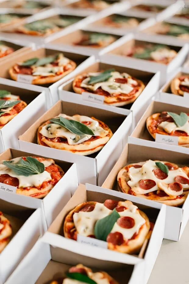 Pizzas in boxes with green leaves