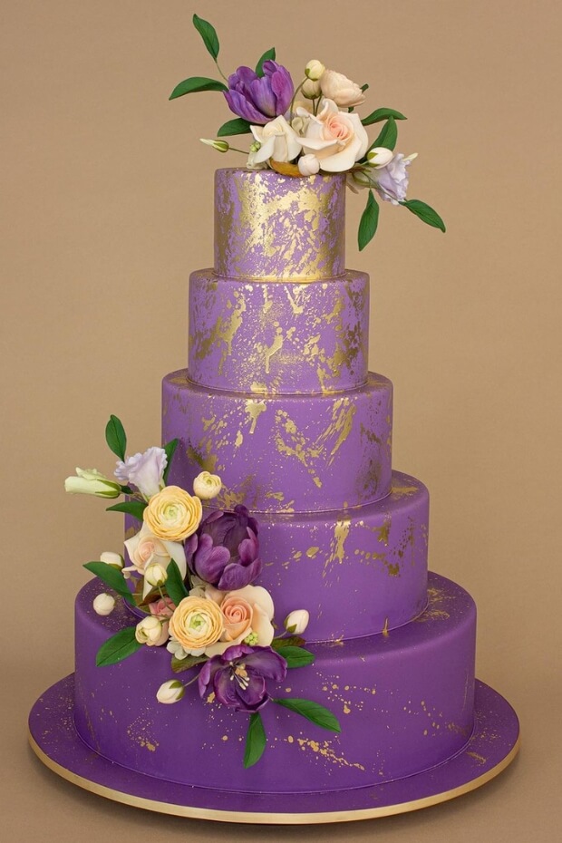 Six-tiered purple wedding cake with gold foil accents