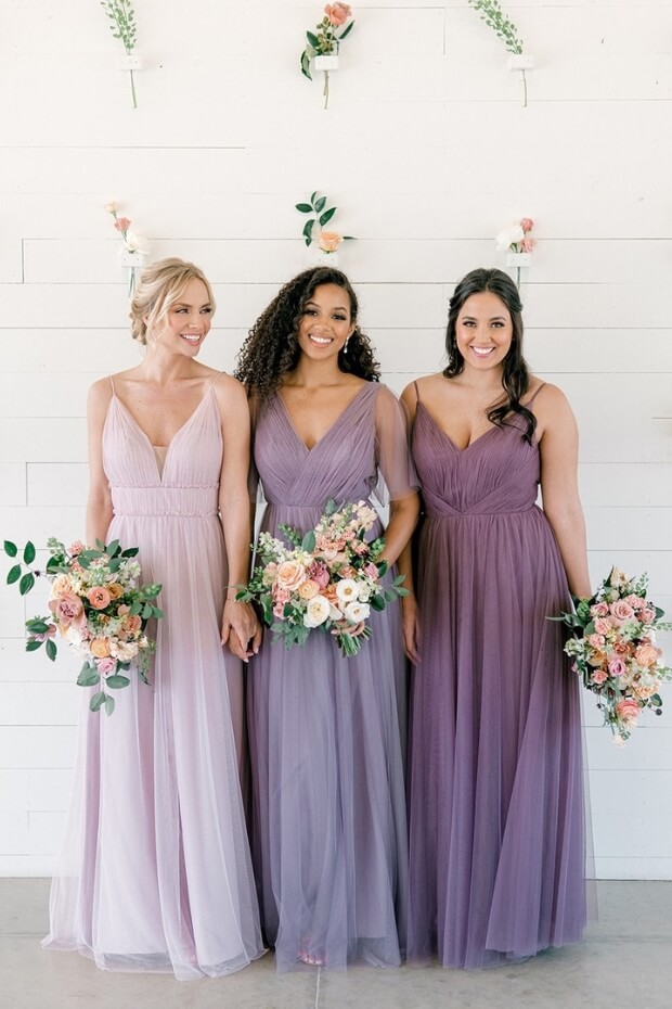 Bridesmaids in smiling pose wearing purple dresses