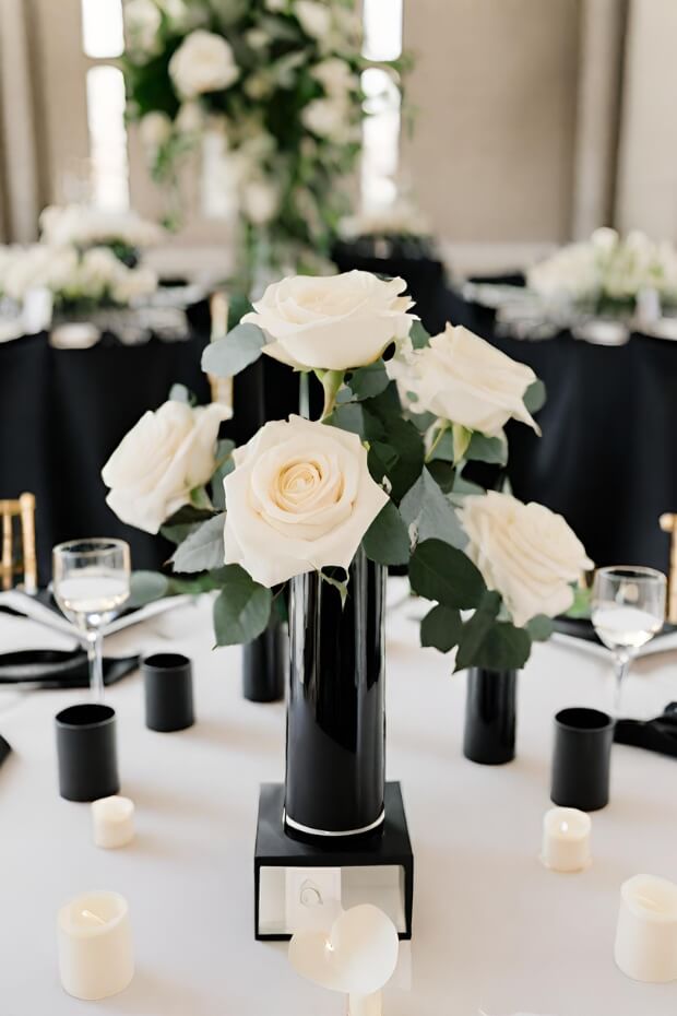 White rose in black vase with candles