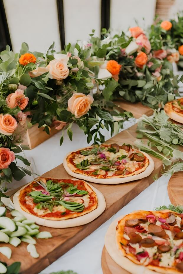 Wooden table with assorted pizzas and flowers