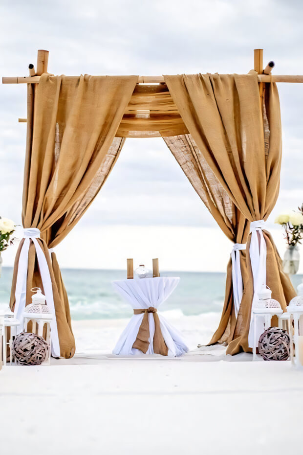 Outdoor wedding arch with burlap drapes