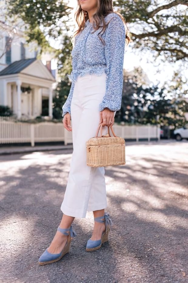 Summer wedding guest outfit with blue floral blouse, white jeans, espadrilles, and basket mini bag