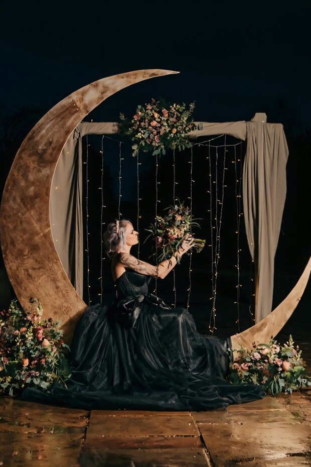 Bride sitting on dark crescent moon with greenery
