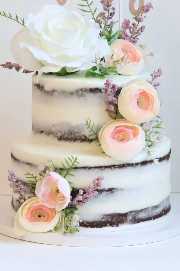 Naked boho cake adorned with fresh flowers and greenery