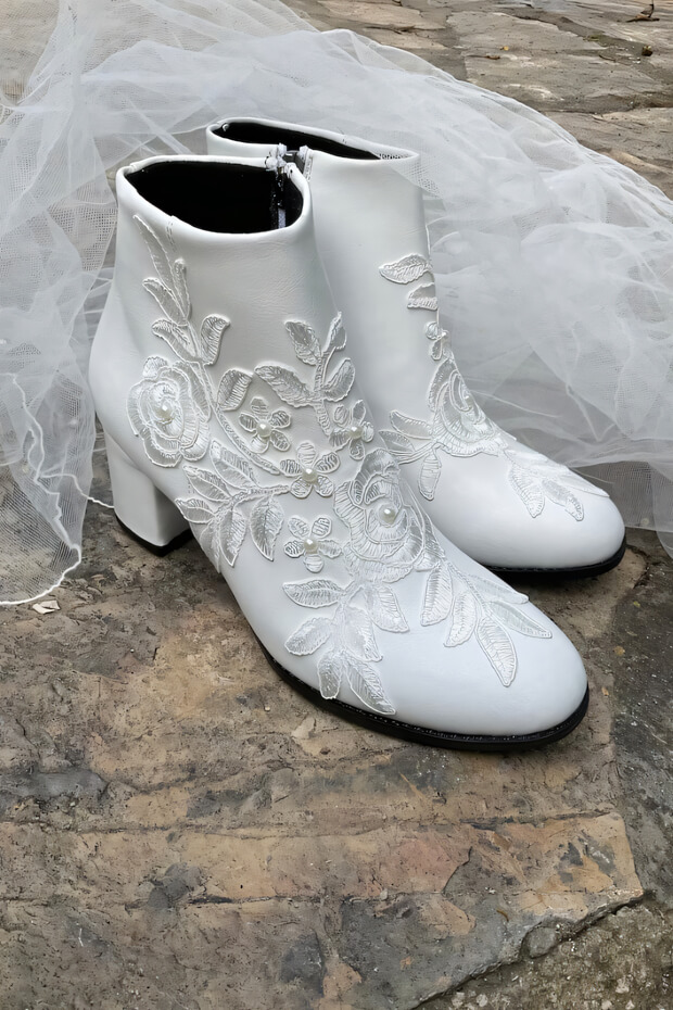 White boots with floral embroidered design, leather, and pointed toe.