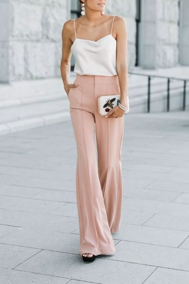 White spaghetti strap top, blush trousers, platform shoes, statement earrings, and box clutch