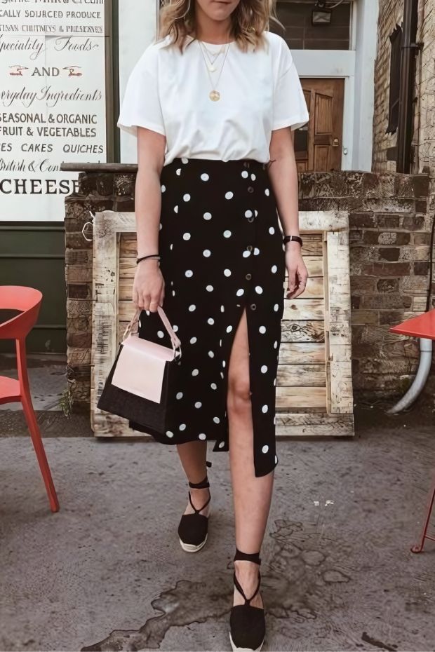 White t-shirt, black polka dot midi skirt with a slit, black espadrilles, and a two-tone bag