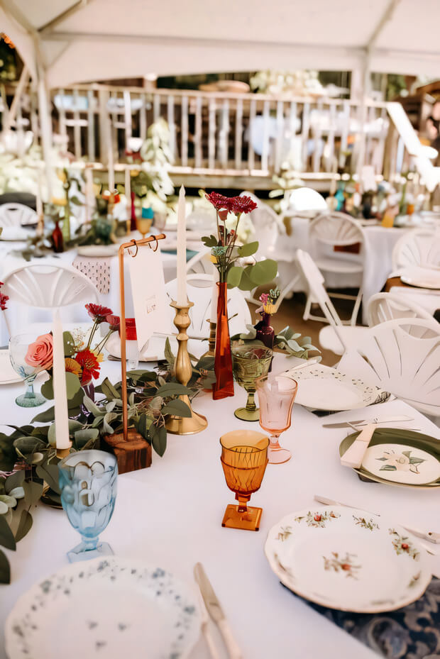 Bright enchanted forest wedding tablescape with floral print plates, gilded candleholders