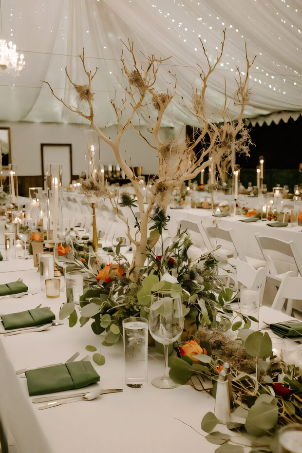 Fab indoor enchanted forest wedding reception space with green linens, bright blooms
