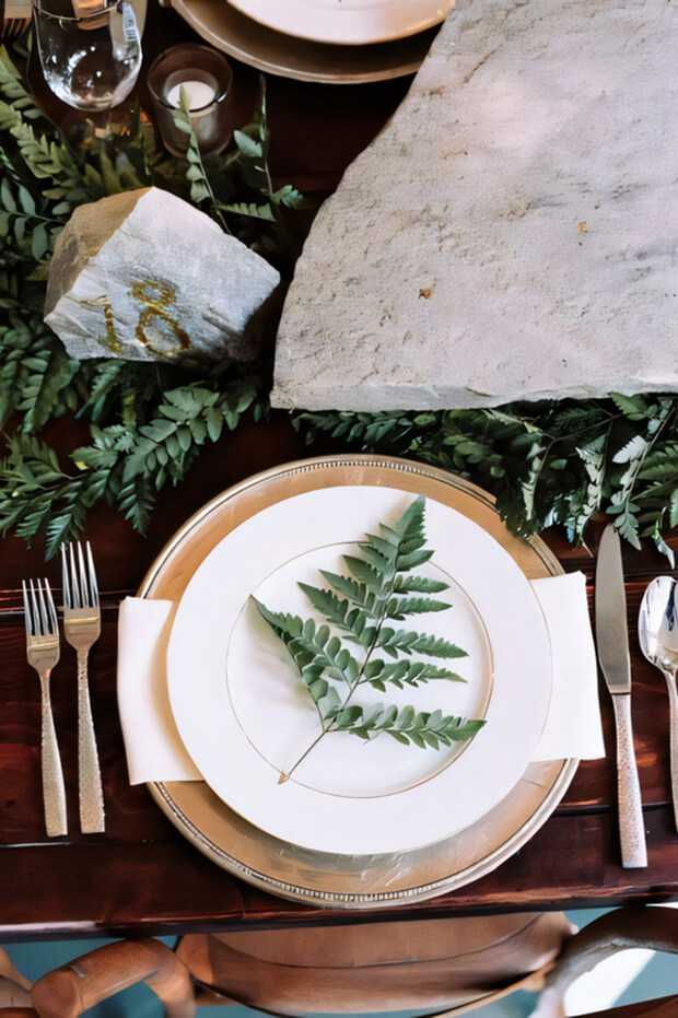 Lovely enchanted forest wedding tablescape with ferns, gilded rock