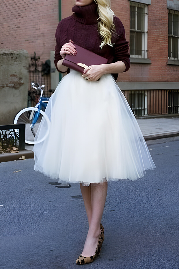 Winter wedding guest outfit with white tutu skirt and purple sweater